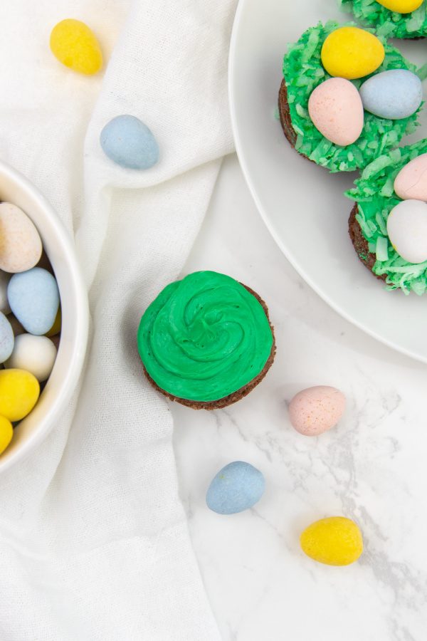 Easter nest brownie bites are a mini brownie topped with a marshmallow frosting, colored coconut and candy eggs. An easy Easter treat! #passion4savings #easter #dessert #bitesize #holiday #birdnest #kidfriendly #best mini brownies in muffin tin