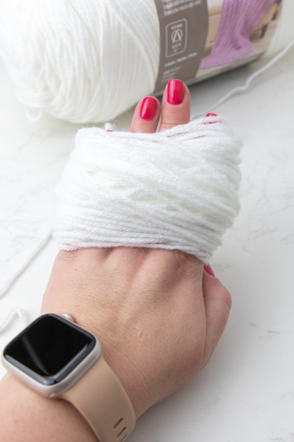 yarn wrapped around hand for wreath craft 