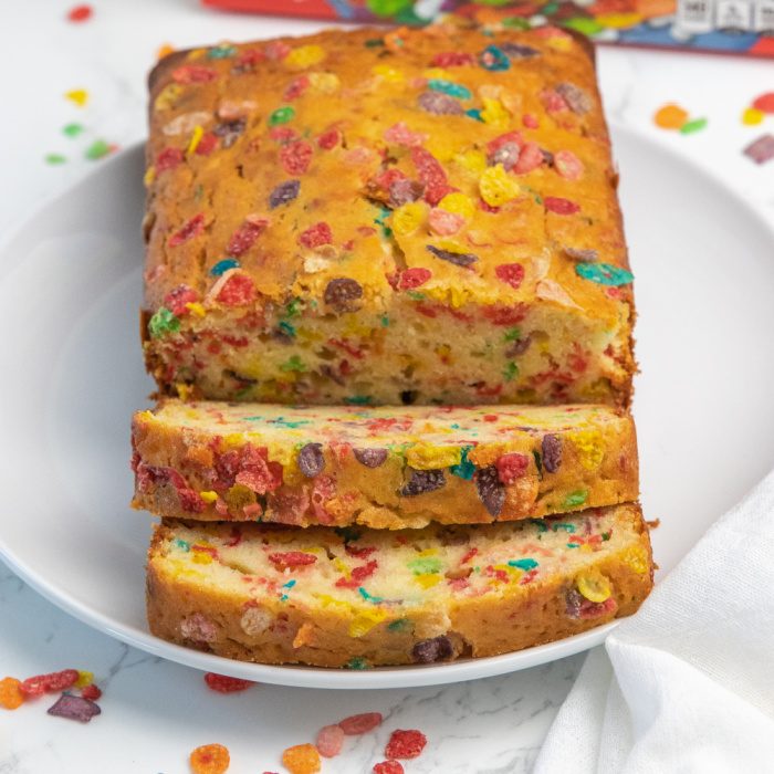 Whip up this Fruity Pebbles bread! A quick bread recipe that is studded with sweet Fruity Pebbles in each bite. A must try dessert bread. #dessert #fruitypebbles #cereal #bread #snack #howtomake #breadrecipe #quickbread #cerealdessert fruity pebble dessert bread on plate