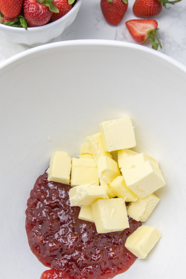 Here is our tried and true strawberry frosting recipe. 3 ingredients with big flavor. Use for cakes, cookies, cupcakes and more. #passion4savings #frosting #strawberries #dessert #strawberrypreserves #3ingredients #easy #best #triedandtrue strawberry preserves in bowl with butter