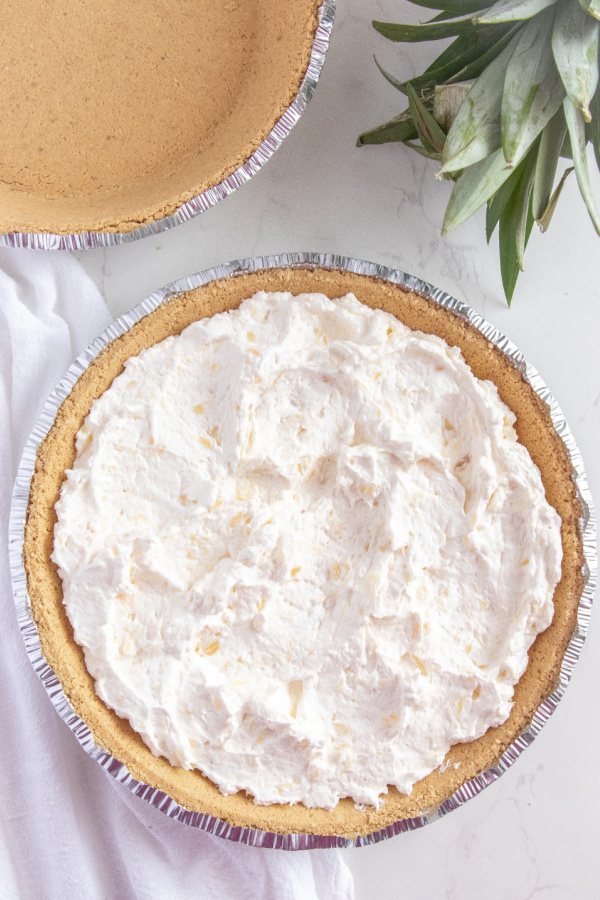 Dole whip pie is a creamy pineapple pie that is made with crushed pineapple and cream cheese. So easy and a tasty no bake pineapple recipe. #passion4savings #Pineapple #pie #dolewhip #easy #nobake #summer #spring #potluck #makeahead no bake summer pie