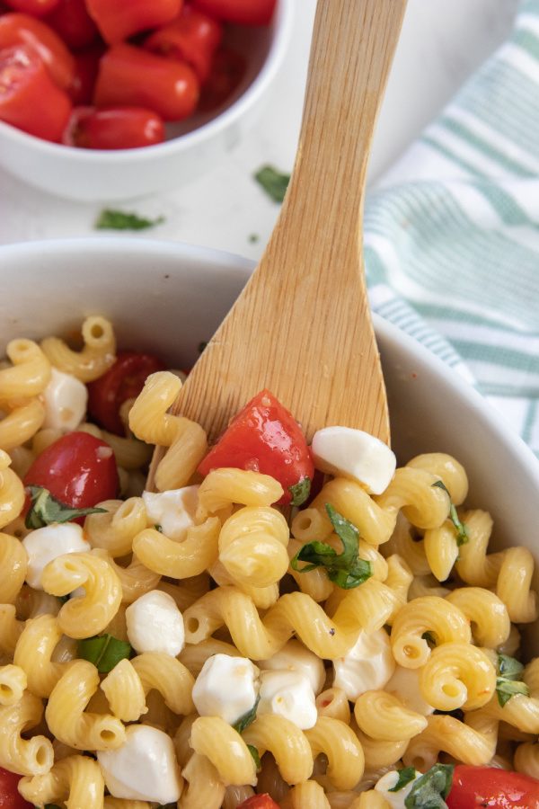 pasta salad in bowl with wooden spoon