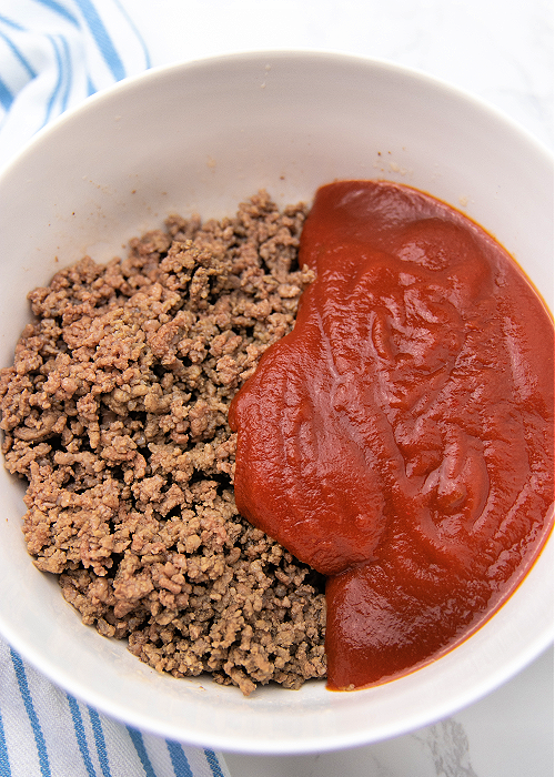 ground beef and sauce in a white mixing bowl