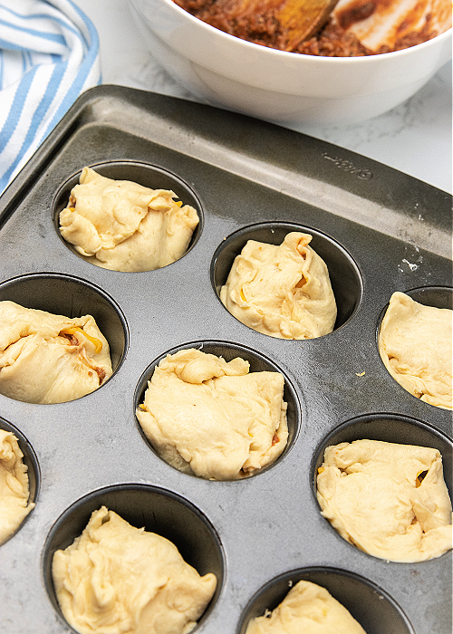 unbaked cheesy sloppy joe bombs in a muffin tin