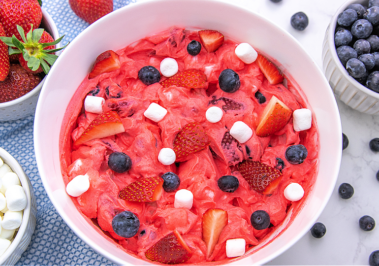 patriotic cheesecake fluff salad in a white bowl with a blue napkin nearby