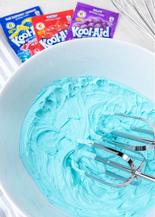 This Whipped Kool-Aid for kids is the perfect indoor activity when it's too hot outside. Or make it as a surprise treat! Children love it! blue koolaid whipped topping in a white mixing bowl