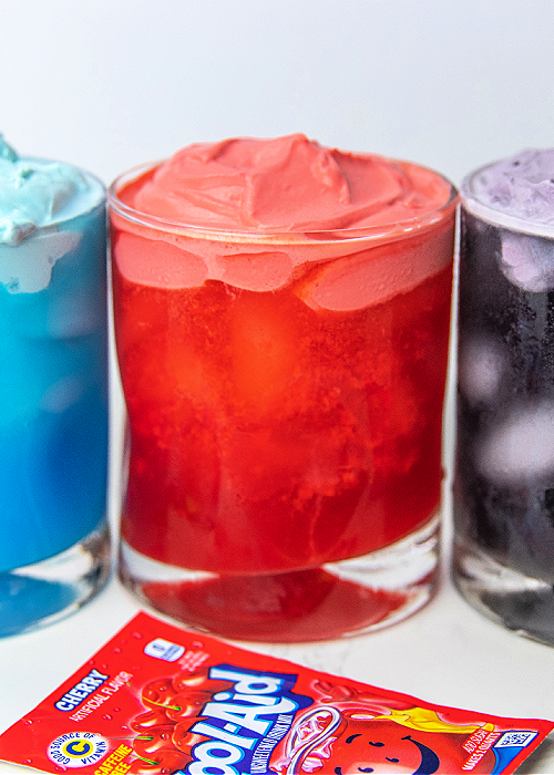 This Whipped Kool-Aid for kids is the perfect indoor activity when it's too hot outside. Or make it as a surprise treat! Children love it! three glasses of whipped kool aid in blue red and purple