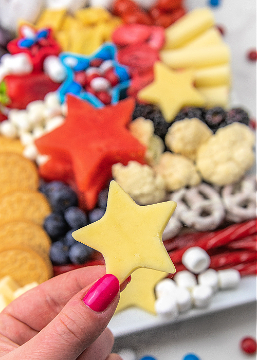 cheese cut out with a star cookie cutter with a 4th of july charcuterie board in the background