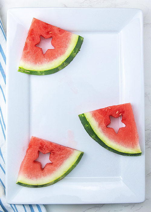 watermelon wedges on a white serving platter with a star cut from each one
