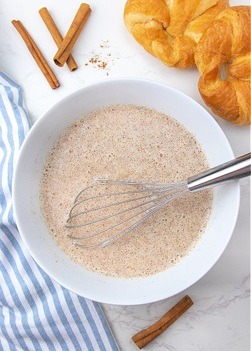French Toast Muffins are delicious and easy to bake! Cinnamon and croissants combine for mega flavor in a convenient muffin-size serving! egg mixture for french toast muffins being whisked in a mixing bowl