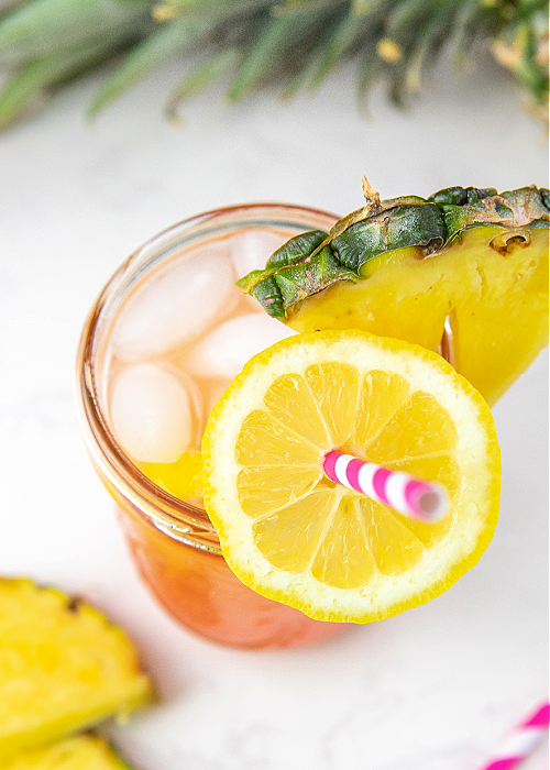 an overhead view of pineapple pink lemonade with a pink and white striped straw