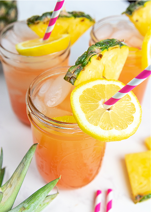 three mason jars with pineapple pink lemonade and pink straws