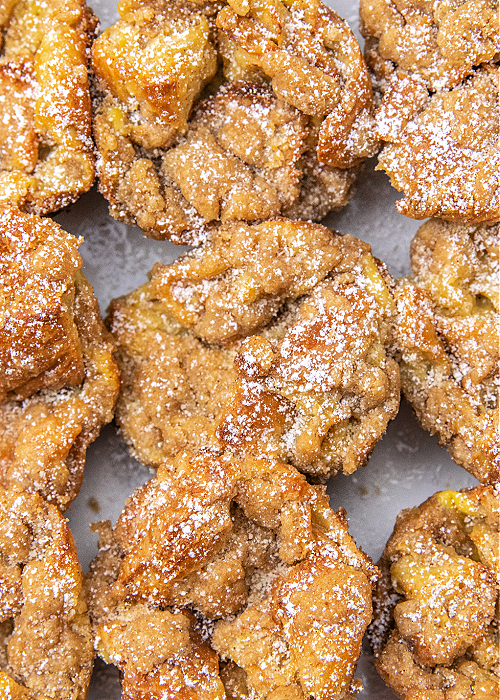 French Toast Muffins are delicious and easy to bake! Cinnamon and croissants combine for mega flavor in a convenient muffin-size serving! french toast muffins on a serving platter with powdered sugar sprinkled on them