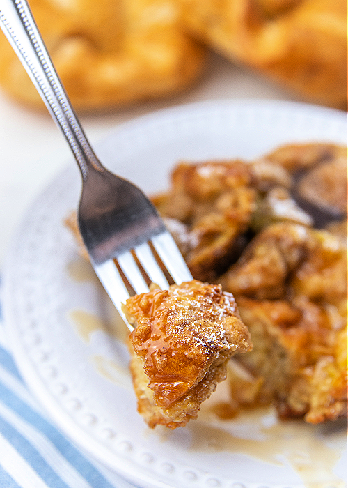 French Toast Muffins are delicious and easy to bake! Cinnamon and croissants combine for mega flavor in a convenient muffin-size serving! a forkful of french toast muffin with a striped napkin