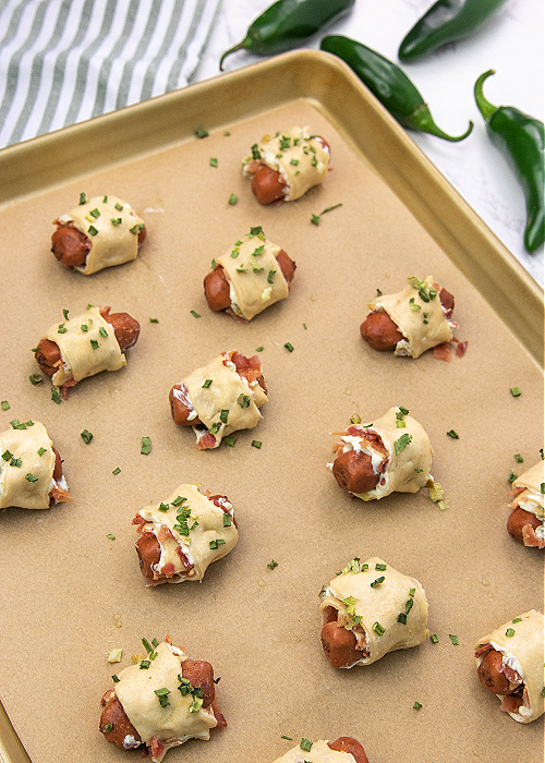 jalapeno popper pig in a blankets on a baking sheet ready to bake