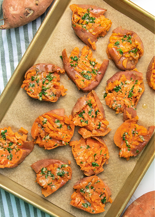 These Garlic Parmesan Smashed Sweet Potatoes are the perfect modern addition to your Thanksgiving meal or any dinner, for that matter! parsley and garlic on smashed sweet potatoes