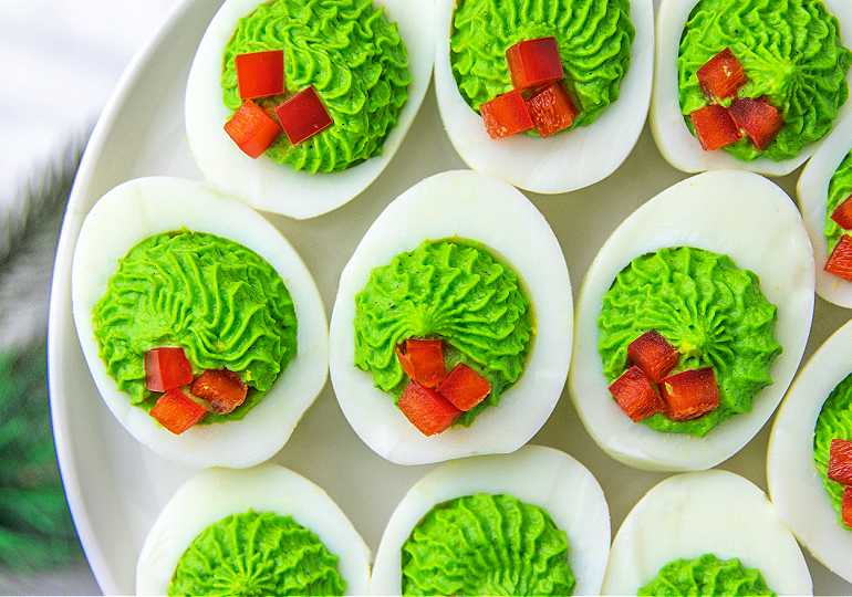 red and green christmas deviled eggs on a serving tray