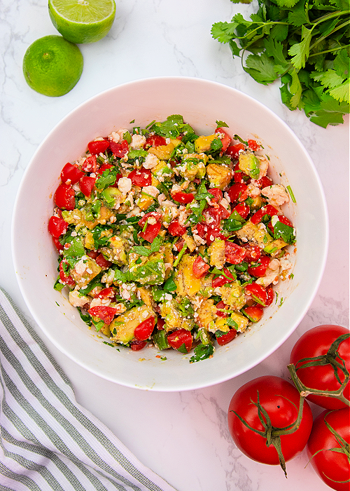 Avocado Crack Dip is SO fresh and flavorful and the perfect gameday dip recipe! Spices, cilantro, feta cheese and more combine for the perfect scoopable game day snack! avocado crack dip in a mixing bowl
