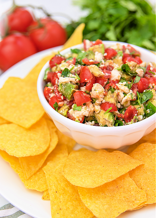 Avocado Crack Dip is SO fresh and flavorful and the perfect gameday dip recipe! Spices, cilantro, feta cheese and more combine for the perfect scoopable game day snack! avocado crack dip with feta cheese in a serving bowl with tortilla chips