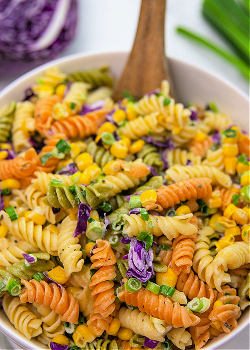 purple, green, and yellow pasta salad for mardi gras in a white serving dish