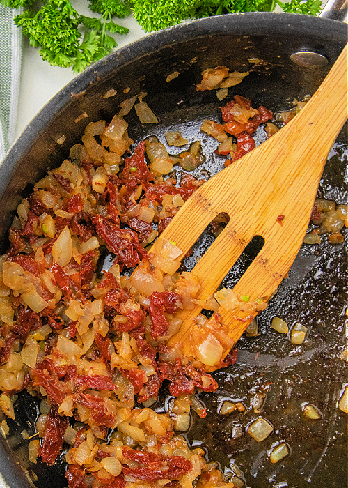 Creamy Garlic Butter Tuscan Shrimp Pasta is a delicious one-pan meal that is healthy, too! Sun-dried tomatoes, parmesan, garlic, and herbs combine for impeccable flavor! sun-dried tomatoes and onions sauteed in a skillet