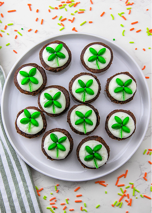 Shamrock M&M Brownie Bites are easy to make and so festive for St. Patrick's Day! Place the candy and you're done decorating! a white serving tray of mini shamrock M&M brownie bites