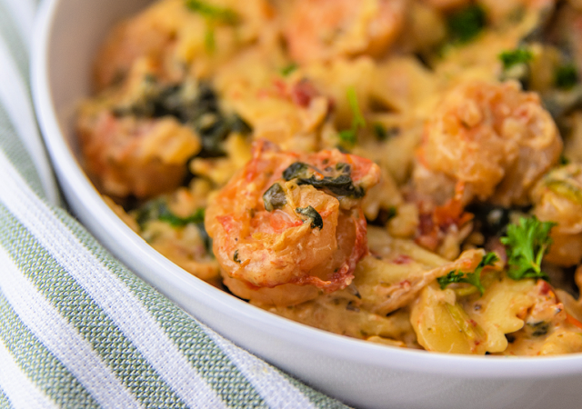 creamy garlic butter tuscan shrimp pasta in a white bowl