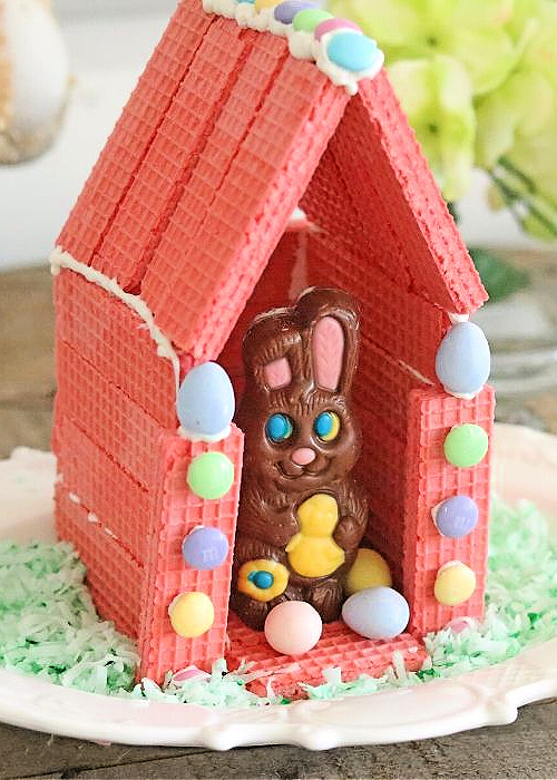 a chocolate easter bunny in a handmade pink wafer house