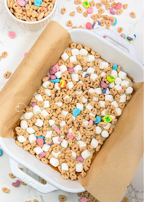These Lucky Charms Magic Cookie Bars combine cereal with a classic! Perfect for St. Patrick's Day, this dessert is easy to make and looks festive, too! bottom layers of lucky charms magic cookie bars before baking