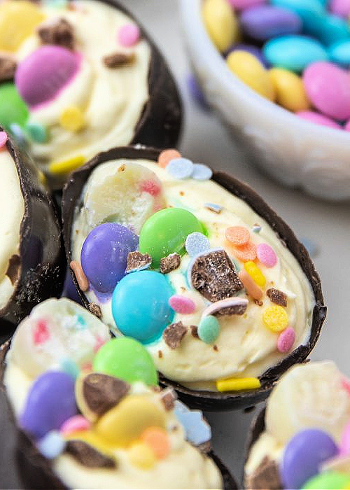Over 20+ Easter Dessert Recipes that are CUTE and EASY to make for all your holiday occasions! Perfect for egg hunts, Easter dinner, and more. loaded cheesecake easter eggs topped with crushed M&Ms