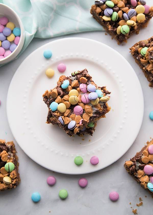 Over 20+ Easter Dessert Recipes that are CUTE and EASY to make for all your holiday occasions! Perfect for egg hunts, Easter dinner, and more. M&M Easter Bars with pastel M&Ms on a white serving plate