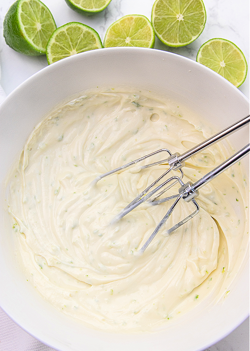 Batter for key lime pie dip in a white mixing bowl