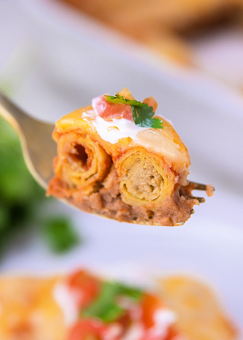 a forkfull of lazy enchilada casserole made with frozen taquitos