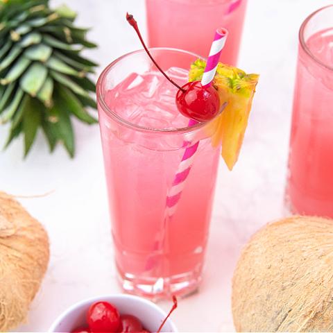 pink pina colada punch garnished with pineapple and a cherry