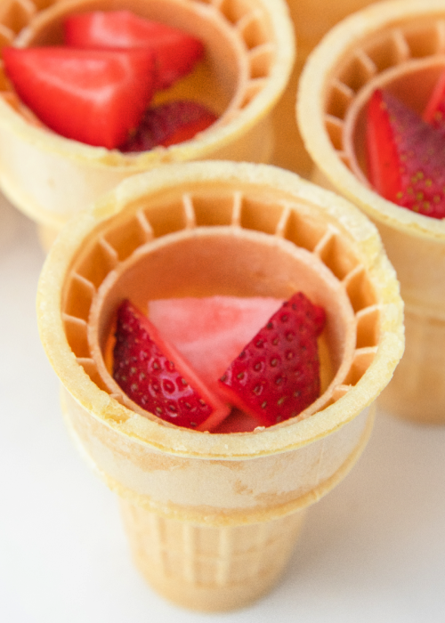 strawberries layered with cheesecake in an ice cream cone