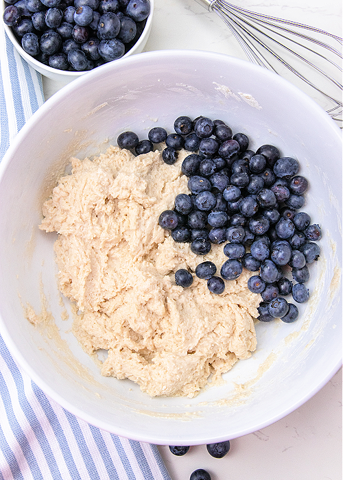 biscuit dough and blueberries in a white mixing bowl