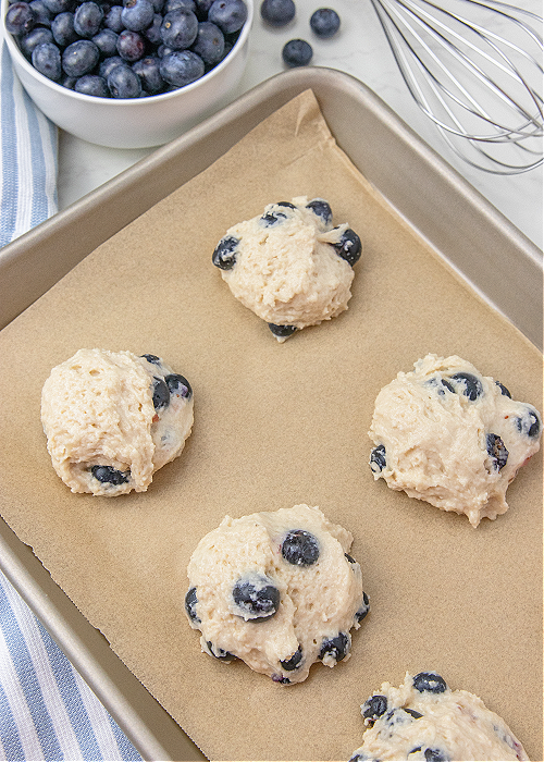 unbaked blueberry biscuits on a baking sheet covered in parchment paper