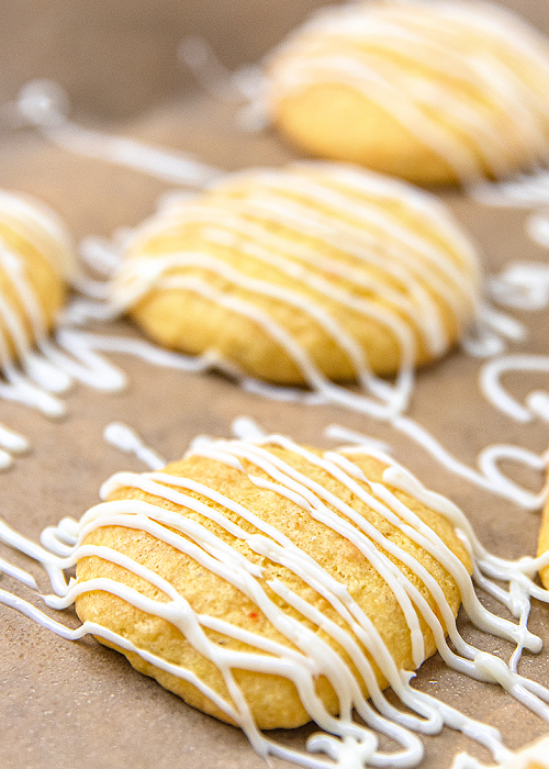 banana bread cookies drizzled with vanilla frosting, cooling on parchment paper