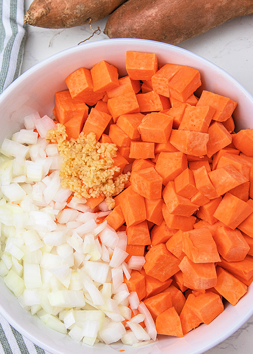 sweet potatoes onions and garlic in a mixing bowl